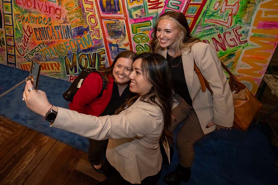 group of three women taking a self in front of mural at Celebrate 2024