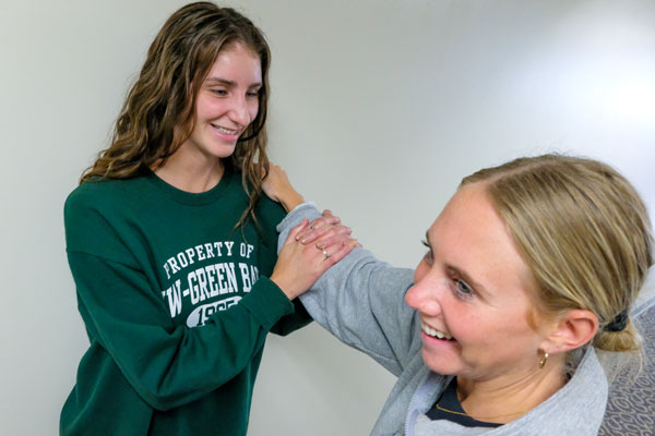 Sport, Exercise & Performance Psychology student practices helping peer stretch shoulder