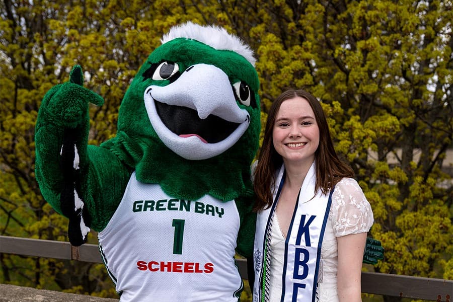 UWGB grad posing with Phlash the Phoenix mascot
