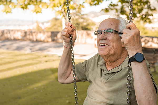 Older man smiling on a swing