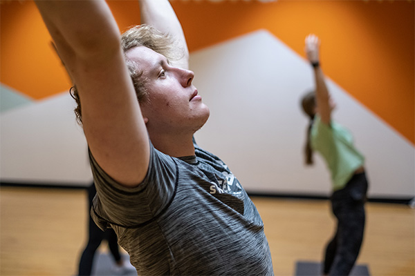 Student standing with arms extended in mountain pose