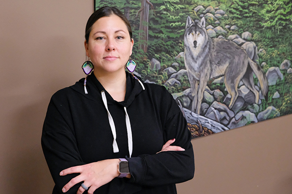 Native American woman in front of wolf painting