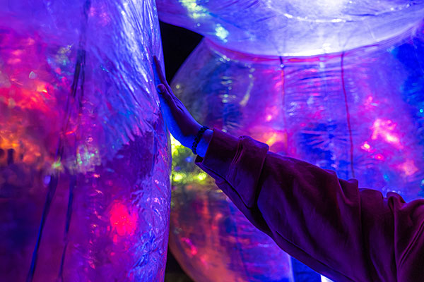 Hand touching Evanescent bubbles interactive art installation piece