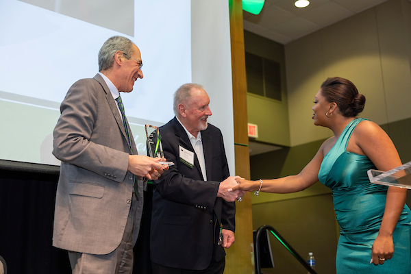 Alumni shaking hands with man on stage