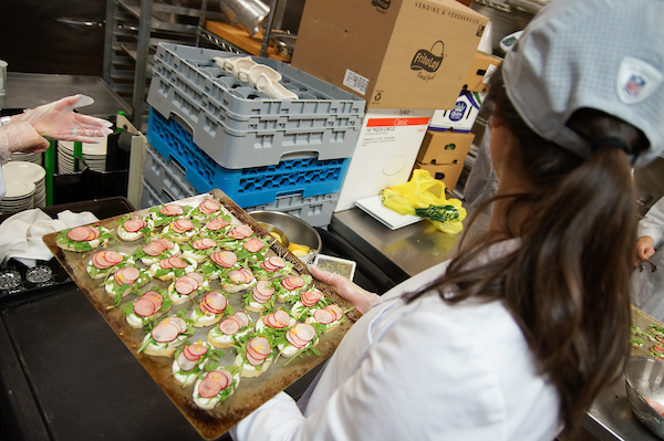 Student carrying appetizer on serving tray