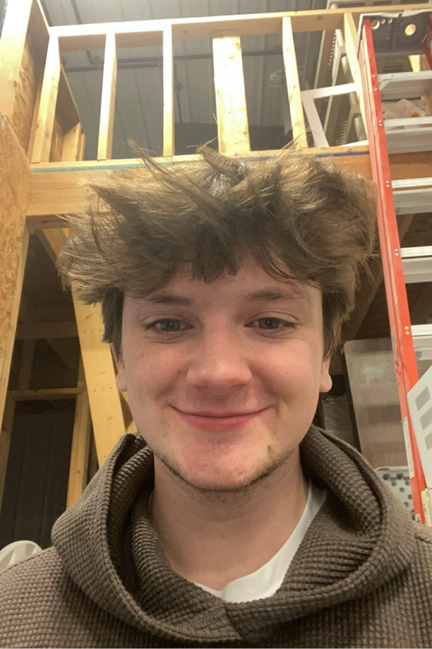 Male student with a ladder and lumber in the background