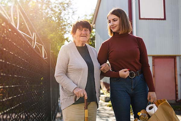 caregiver walking outside with senior woman