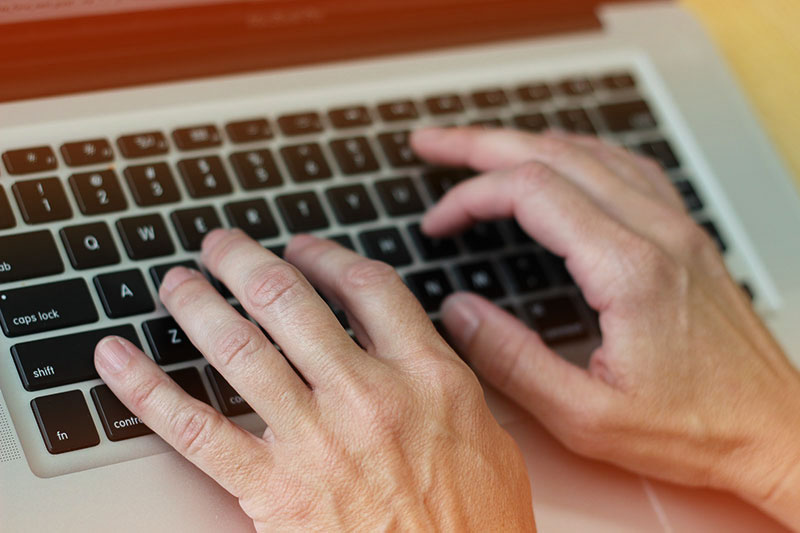 Hands typing on a laptop keyboard