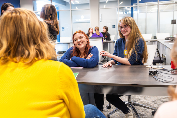 Three students talking around table