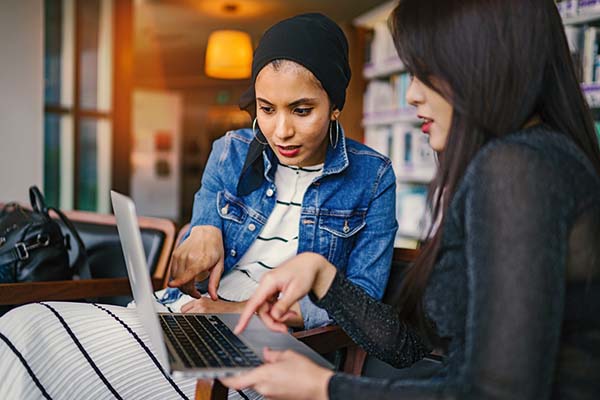 Two women sitting looking at laptop screen