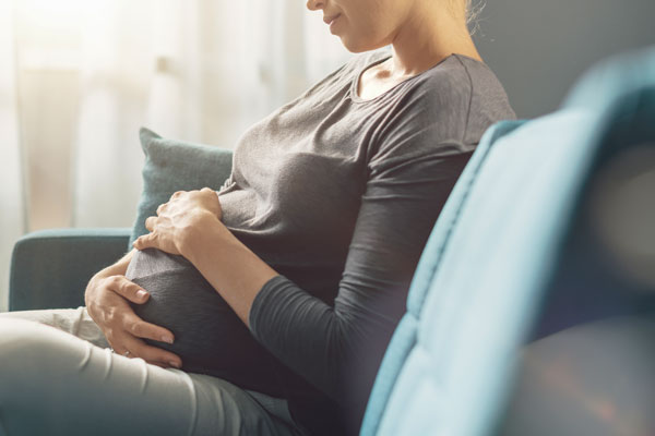 Pregnant woman holding sitting on couch