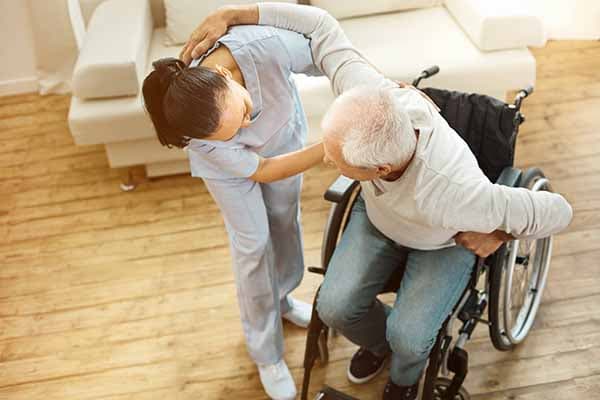 caregiver helping man get up from wheelchair