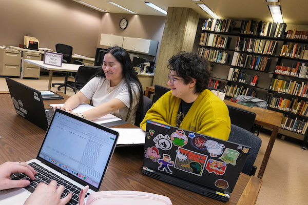 Two students on laptops looking at Asian American archives