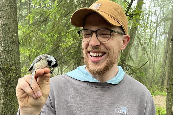 Smiling man with bird perched on hand