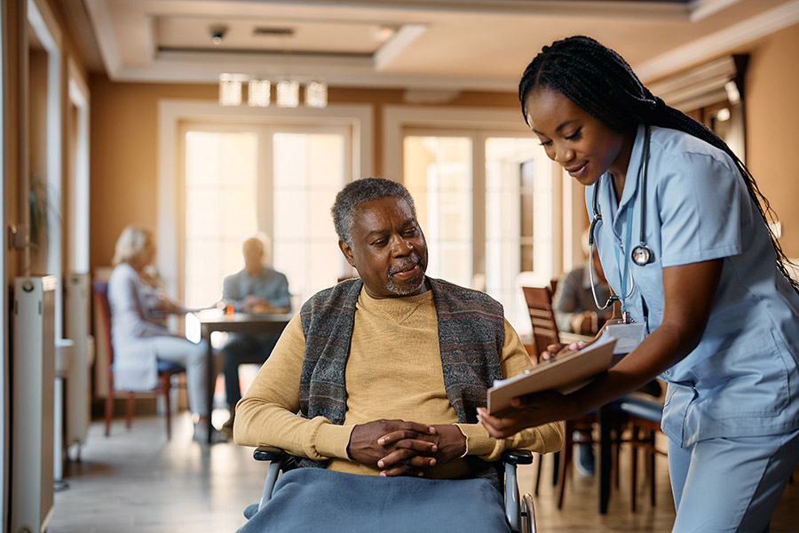 Young nurse assisting older man in wheelchair