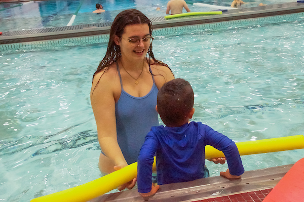 Swim coach teaching camper to swim