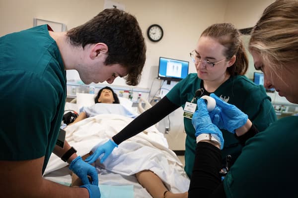 Students in scrubs working in sim lab