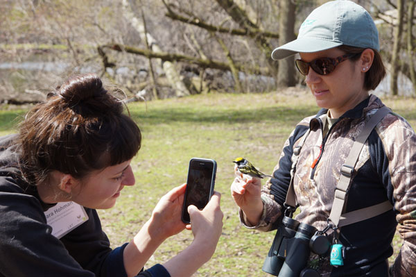 Student taking picture of bird on phone