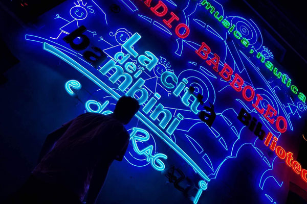 Study standing in front of neon signs