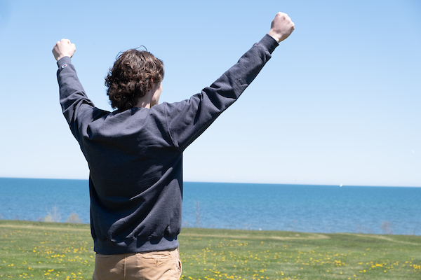 Student posing with outstretched arms by the bay