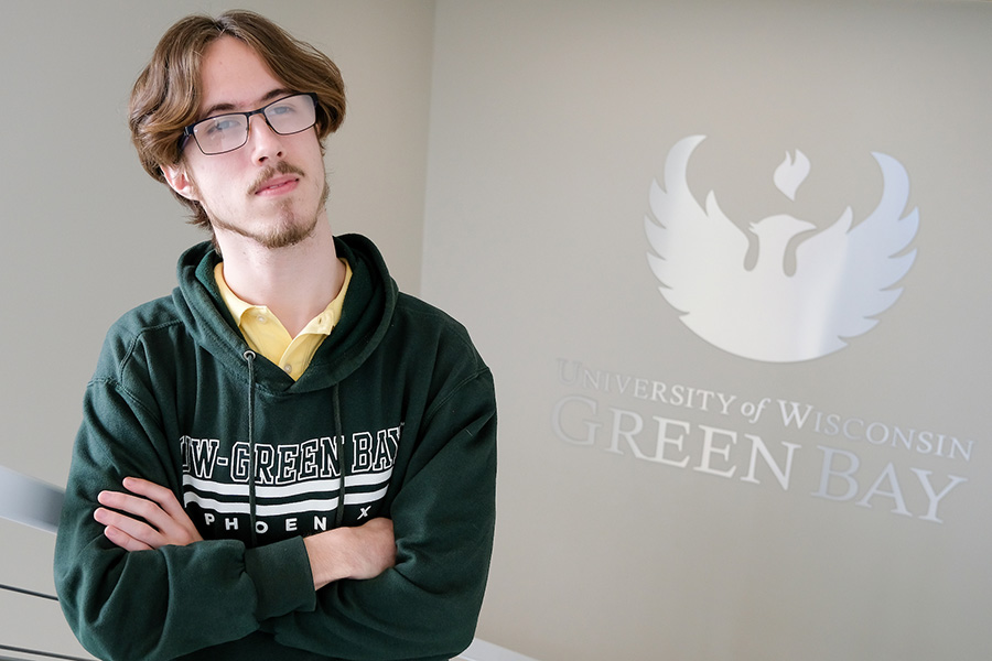 Student with thoughtful gaze on stairway near UW Green Bay logo