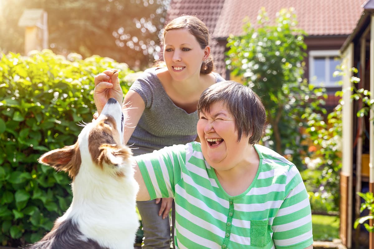 woman with disability outside with her caregiver and a dog