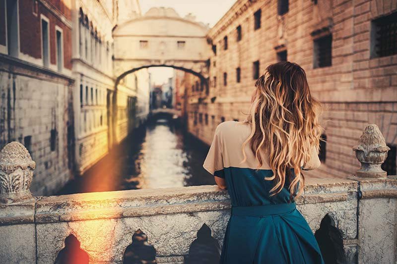 woman standing on a bridge overlooking a canal in Italy learn Italian