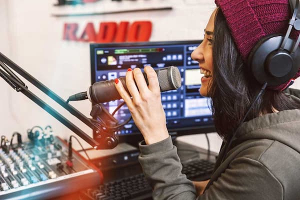 A woman speaking into a microphone in a studio.